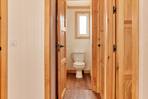 Binnenzicht van een badkamer met houten panelen en een toilet in Bungalow Premium Levante, TAIGA Conil, Spanje.