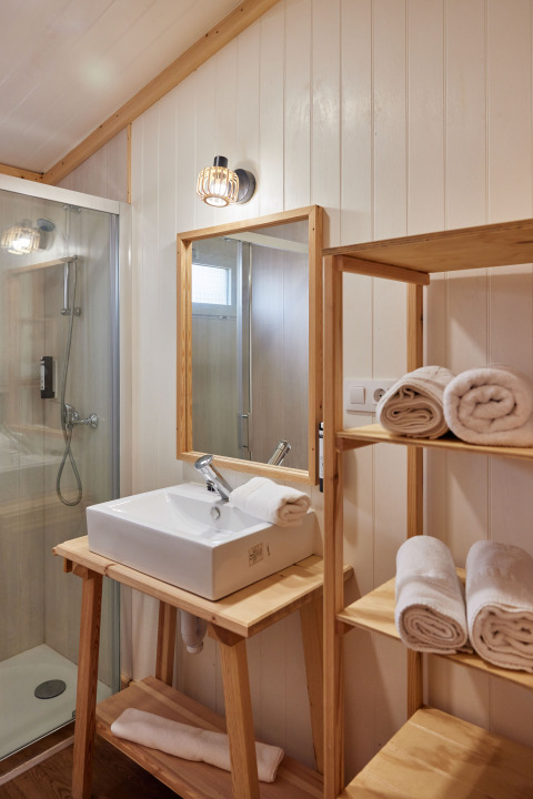Salle de bain moderne du Bungalow Premium Levante à TAIGA Conil, avec douche, vasque et serviettes.