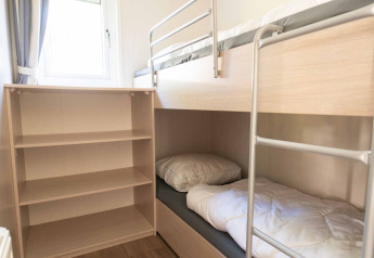 Vista de un dormitorio compacto con literas y estantería en Easy chalet, Eurocamping Vessem, Países Bajos.