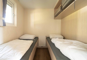 Dos camas individuales en una habitación luminosa del Easy chalet, Eurocamping Vessem BV, Países Bajos, con ventana.