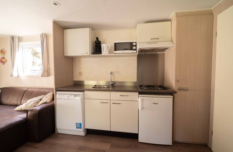 Kompakte Küchenzeile im Easy Chalet bei Eurocamping Vessem BV, Niederlande, mit Sofa und Geräten.