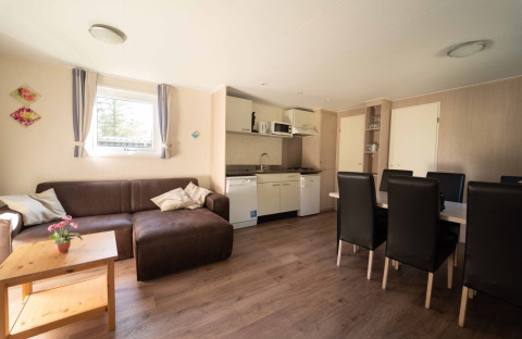 Gemütliches Wohnzimmer und Küchenzeile im Easy Chalet bei Eurocamping Vessem BV, Niederlande, mit Esstisch.