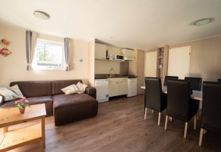 Gemütliches Wohnzimmer und Küchenzeile im Easy Chalet bei Eurocamping Vessem BV, Niederlande, mit Esstisch.