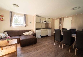 Indbydende opholdsstue og tekøkken i Easy chalet på Eurocamping Vessem BV, Nederlandene, med spisebord.