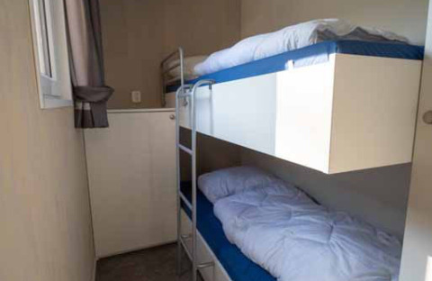 Habitación compacta con literas en Woodlodge XL en Eurocamping Vessem BV, Países Bajos, con ventana luminosa.