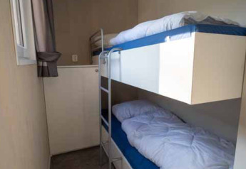 Habitación compacta con literas en Woodlodge XL en Eurocamping Vessem BV, Países Bajos, con ventana luminosa.