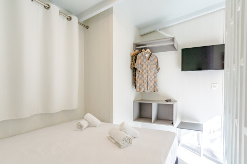 Habitación luminosa y compacta en Amos Studio, Camping Costa del Sol Glamping Village, con cama, TV y ropa.