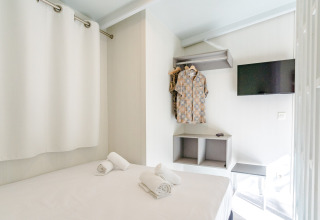 Camera luminosa e compatta ad Amos Studio, Camping Costa del Sol Glamping Village, con letto, TV e vestiti.