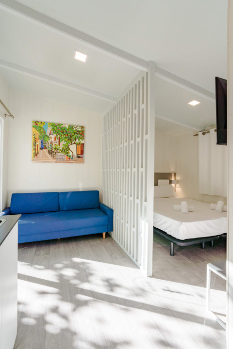 Lichte studio bij Camping Costa del Sol Glamping Village in Spanje met blauwe zetel en bed achter tussenwand.