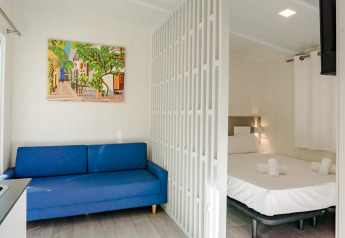 Studio lumineux au Camping Costa del Sol Glamping Village en Espagne, canapé bleu et lit séparé.