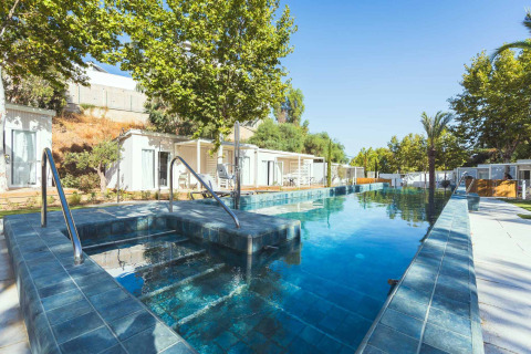 Piscine et spa à Amos Studio du Camping Costa del Sol Glamping Village, entourés de cabanes et d'arbres.