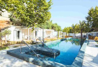 Piscina all’aperto presso Amos Studio, Camping Costa del Sol Glamping Village, circondata da alberi e sedie.
