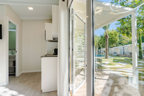 Vista interna da Amos Studio presso Camping Costa del Sol Glamping Village, con patio e giardino visibili fuori.