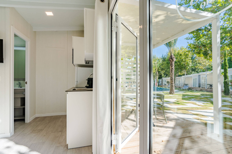 Vista interior de Amos Studio en Camping Costa del Sol Glamping Village, con acceso a terraza y jardines exteriores.