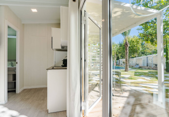 Vista interna da Amos Studio presso Camping Costa del Sol Glamping Village, con patio e giardino visibili fuori.