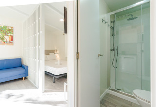 Amos Studio bij Camping Costa del Sol Glamping Village in Spanje met douche, bed, blauwe zetel en modern interieur.