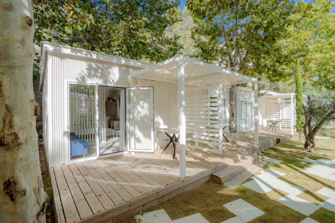 Moderne Amos Studio-lodge met houten terras in Camping Costa del Sol Glamping Village, omgeven door groen.