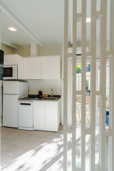 Cocina moderna y compacta de Amos Studio en Camping Costa del Sol Glamping Village, España, con luz natural.