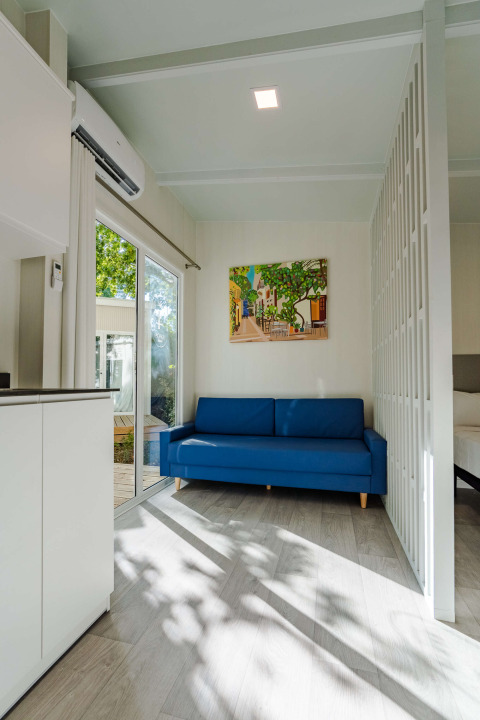 Moderne salon in Amos Studio bij Camping Costa del Sol Glamping Village, blauwe zetel en schilderij.