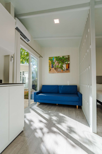 Helles Wohnzimmer im Amos Studio, Camping Costa del Sol, mit blauer Couch und farbigem Wandbild.