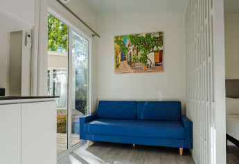 Soggiorno moderno in Amos Studio presso Camping Costa del Sol Glamping Village, divano blu e quadro.