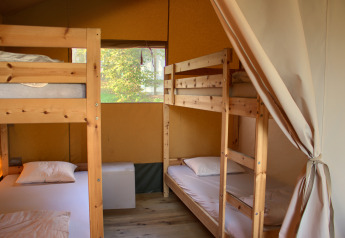 Intérieur d'une tente safari avec deux lits superposés en bois, bien équipé pour un séjour en camping.