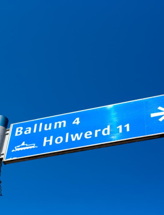 Señal de tráfico hacia Ballum y Holwerd bajo cielo azul cerca de Slappeterp, Frisia, Países Bajos.