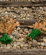 Ramos de flores secas con cintas verdes sobre traviesas y piedras en un parque vacacional de glamping.
