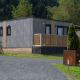 Moderne lodge ved Wulfenia Waterfront, Ossiacher See, Østrig, omgivet af grønne træer og bjerge.