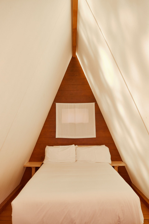Interieur van de Breña Tent bij TAIGA Tarifa in Spanje, met een gezellig bed in een driehoekige kamer.