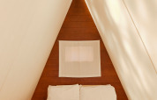 Vista interior de la Breña Tent en TAIGA Tarifa, España, con una cama acogedora en una habitación triangular.