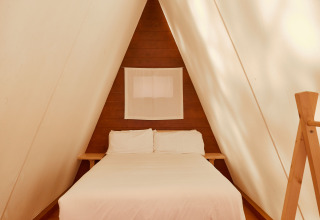 Interior de cabaña minimalista con cama doble en Breña Tent de TAIGA Tarifa, España.
