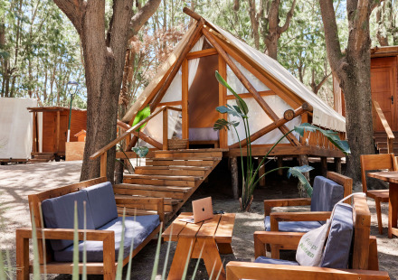 Safari tent Tamaral Tent bij TAIGA Tarifa in Spanje, met buitenterras en houten meubelen tussen de bomen.