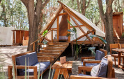 Tente safari Tamaral Tent à TAIGA Tarifa en Espagne, avec salons extérieurs et mobilier en bois sous les arbres.