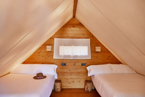 Interieur van de Tamaral safari tent bij TAIGA Tarifa in Spanje, met twee bedden en houten wanden.