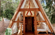 Tienda safari de madera en A con puertas abiertas y luz natural en TAIGA Tarifa, España, bosque alrededor.
