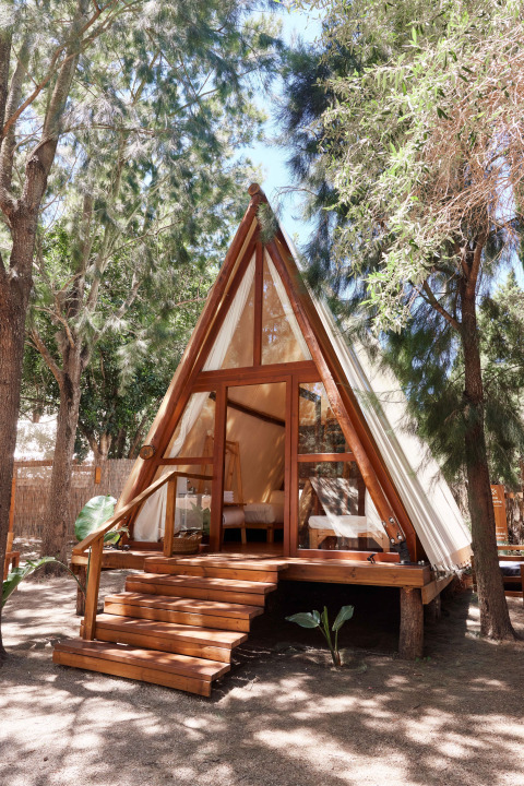 Sauceda Tent bij TAIGA Tarifa in Spanje: A-frame safaritent met houten terras omgeven door bomen.