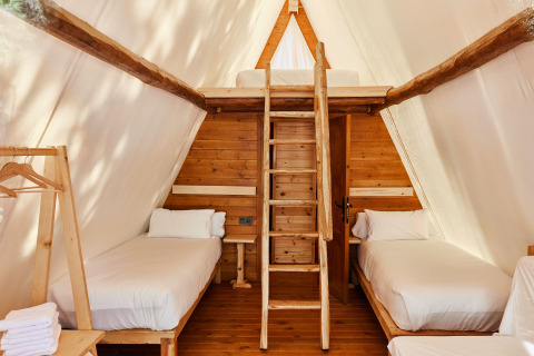 Interieur van Sauceda safari tent bij TAIGA Tarifa, Spanje, met twee eenpersoonsbedden en houten zolder.