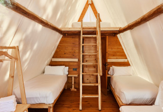 Interieur van Sauceda safari tent bij TAIGA Tarifa, Spanje, met twee eenpersoonsbedden en houten zolder.
