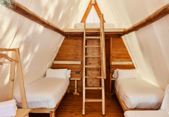 Interieur van Sauceda safari tent bij TAIGA Tarifa, Spanje, met twee eenpersoonsbedden en houten zolder.