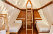 Interior of Sauceda Safari Tent at TAIGA Tarifa, Spain, featuring two single beds and a wooden loft.