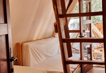 Interno della tenda Sauceda presso TAIGA Tarifa in Spagna, pavimento in legno, scala e luce naturale.