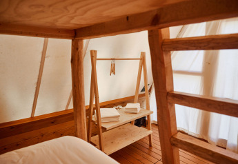 Intérieur de la tente safari Sauceda à TAIGA Tarifa, Espagne, avec des meubles et étagères en bois.