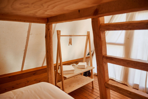 Interno della tenda safari Sauceda presso TAIGA Tarifa in Spagna con mobili e scaffali in legno.