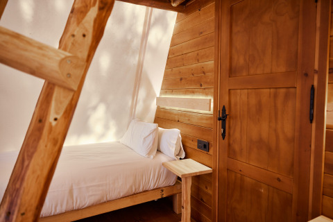 Interior de la tienda Sauceda en TAIGA Tarifa, España, con paneles de madera, cama y escalera.