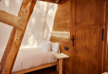 Intérieur de la tente Sauceda à TAIGA Tarifa, Espagne, avec panneaux en bois, lit et échelle.
