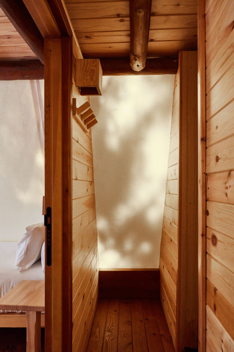 Vue intérieure de la tente Sauceda à TAIGA Tarifa, Espagne, avec murs en bois et lumière naturelle douce.