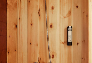 Ducha con paredes de madera en la tienda Sauceda de TAIGA Tarifa, España, con grifería moderna.