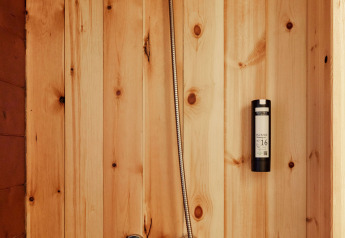 Doccia con pareti in legno nella tenda Sauceda di TAIGA Tarifa, Spagna, con rubinetto moderno.