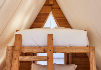 Interior de la tienda safari Algaida Tent en TAIGA Tarifa, España, con literas de madera y paredes claras.